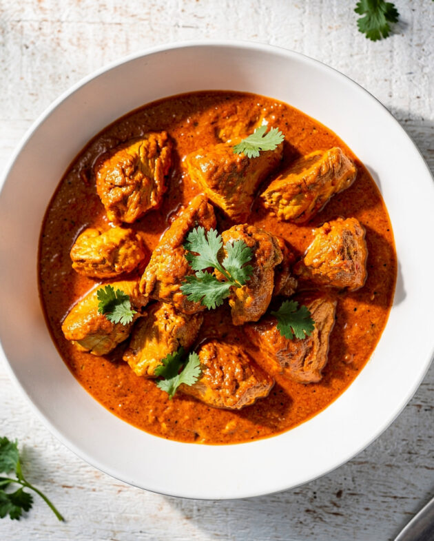 A beautifully plated bowl of homemade chicken tikka masala, featuring tender chicken in a rich, creamy tomato sauce, garnished with fresh cilantro.