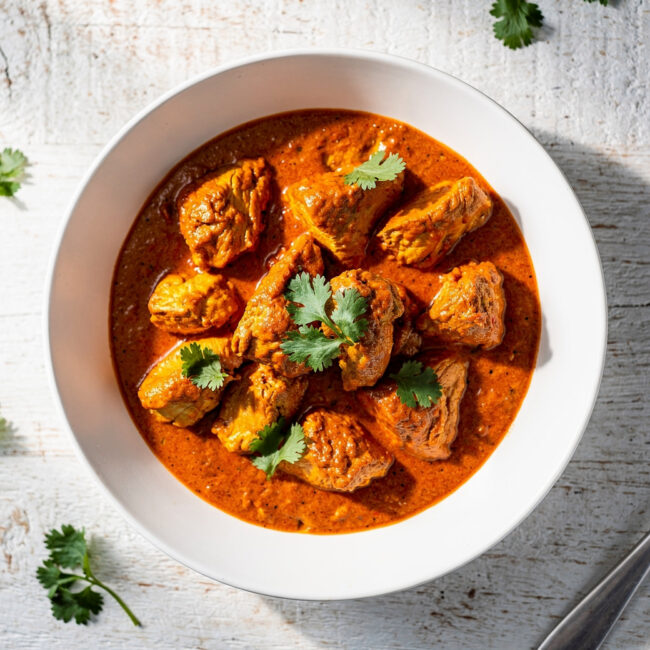 A beautifully plated bowl of homemade chicken tikka masala, featuring tender chicken in a rich, creamy tomato sauce, garnished with fresh cilantro.