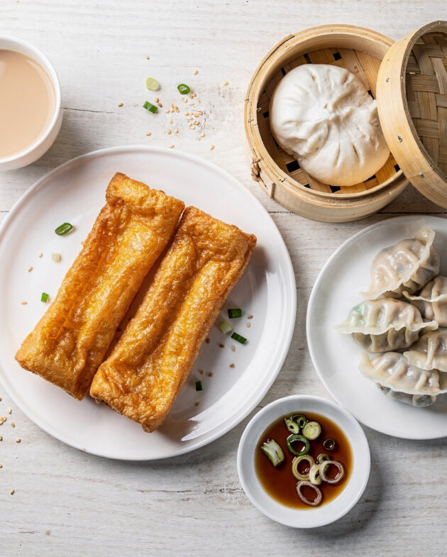A freshly folded jianbing, a popular chinese breakfast, sits on a wooden board with scattered scallions.