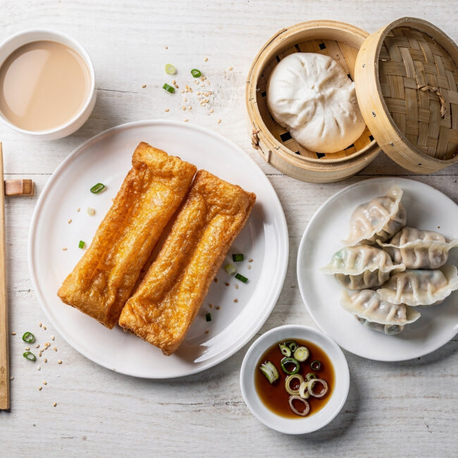 A freshly folded jianbing, a popular chinese breakfast, sits on a wooden board with scattered scallions.