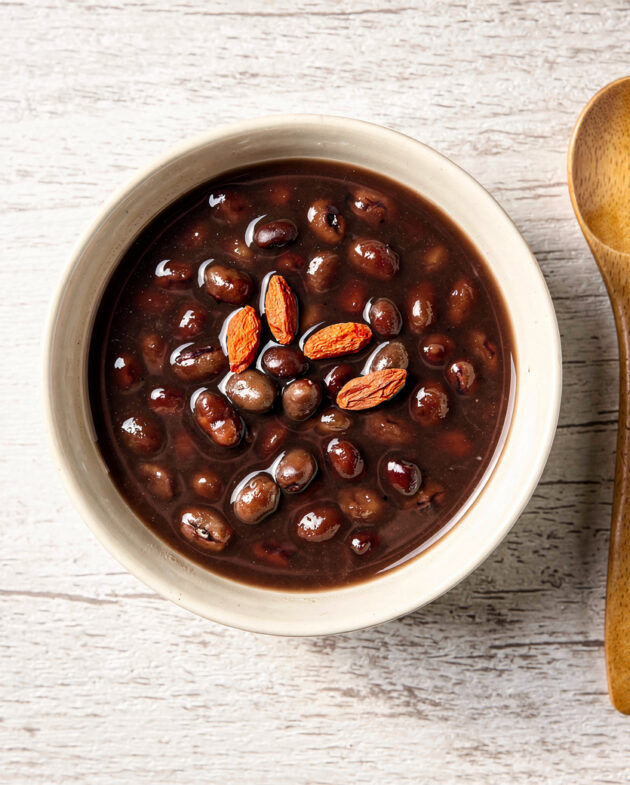 A comforting bowl of traditional chinese desserts, specifically red bean soup, gently steaming and garnished with red goji berries.