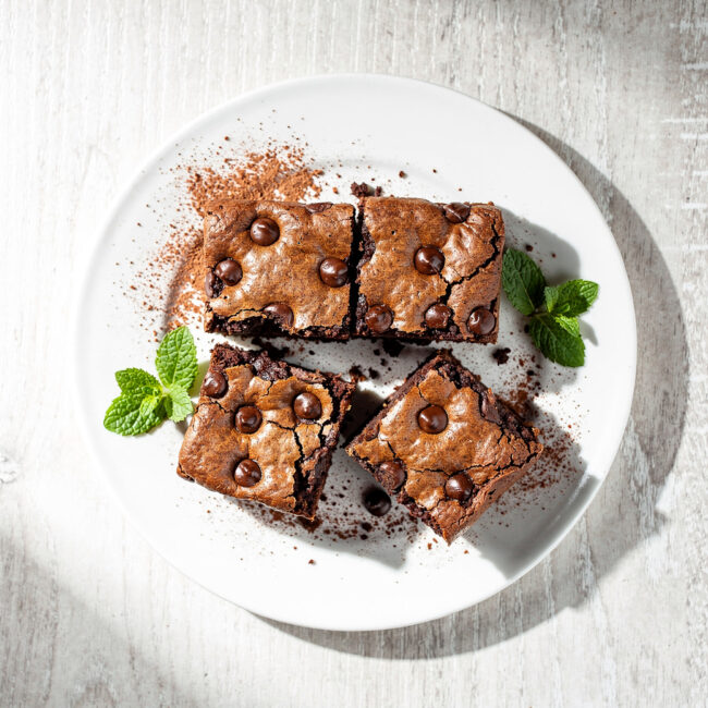 A batch of freshly baked chocolate chip brownies with crackly tops and melty chocolate chips, ready to enjoy.