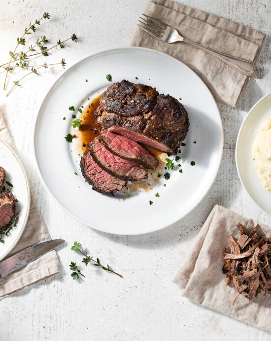 A beautifully plated and tender chuck roast recipe resting in a pool of rich gravy with carrots and onions.