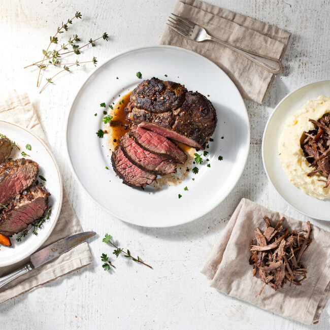 A beautifully plated and tender chuck roast recipe resting in a pool of rich gravy with carrots and onions.