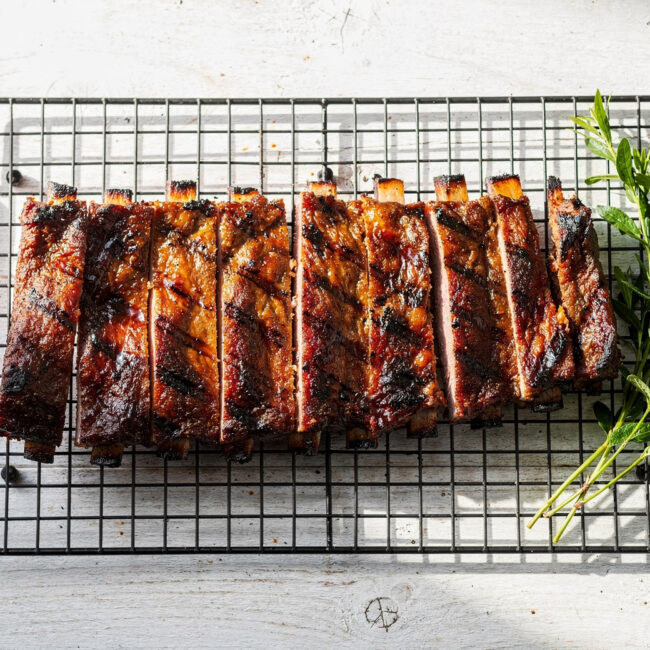 A perfectly grilled rack of ribs showcasing the ideal cook time for ribs on grill, with a dark caramelized crust and visible smoke ring.