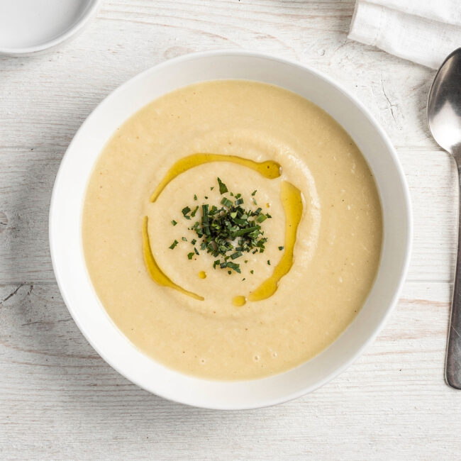 A bowl of homemade creamy potato soup mix garnished with chives and a drizzle of cream.