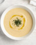 A bowl of homemade creamy potato soup mix garnished with chives and a drizzle of cream.