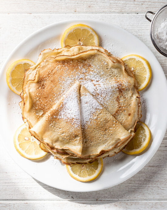A perfectly golden crepe made from our crepe mix recipe, draped over a plate with fresh berries.