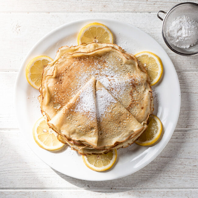 A perfectly golden crepe made from our crepe mix recipe, draped over a plate with fresh berries.