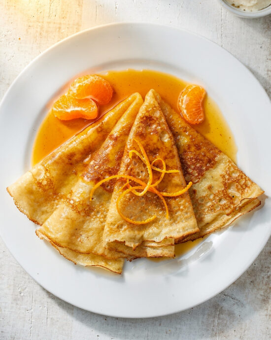 The finished, beautifully sauced crepe suzette recipe served on a classic white plate.