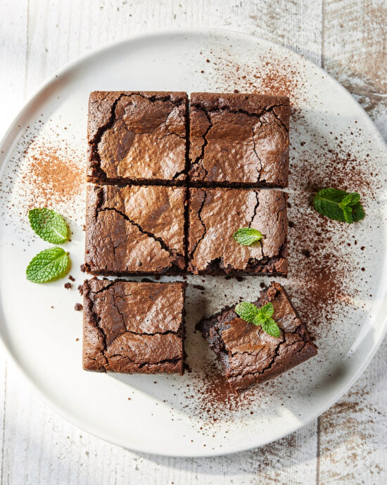A close-up, overhead shot of a pan of freshly baked gluten free brownies with a cracked, shiny top.