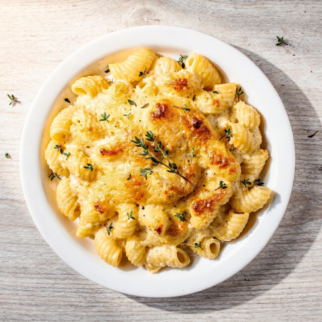 A creamy, golden-brown baked gluten free mac and cheese in a cast iron skillet, ready to serve.