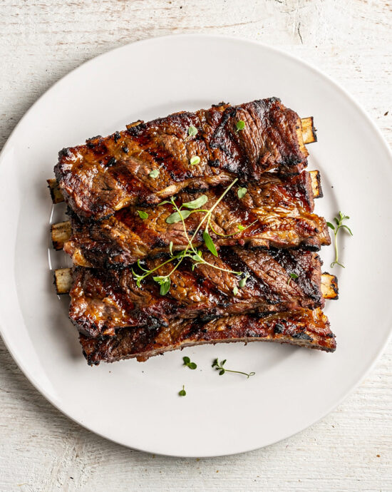 A heaping platter of perfectly grilled beef country style ribs with a glossy, caramelized crust, ready to serve.