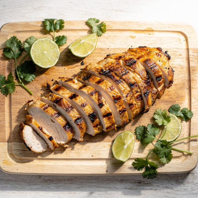 A beautifully plated grilled chicken breast recipe with a golden glaze on a rustic wooden board.