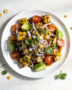 A colorful grilled corn salad with avocado and red onion in a rustic bowl.