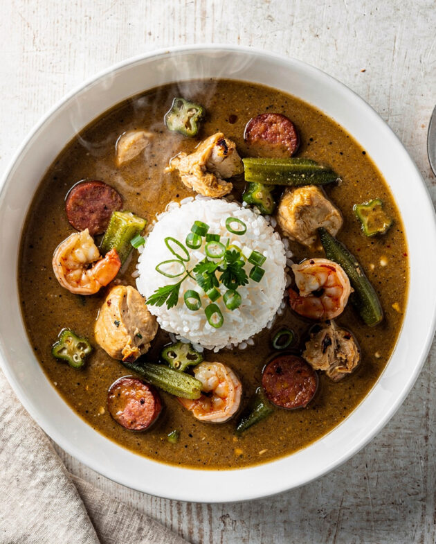 An overhead view of a hearty gumbo recipe served in a rustic bowl over rice.