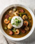 An overhead view of a hearty gumbo recipe served in a rustic bowl over rice.