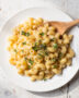 A creamy bowl of healthy mac and cheese topped with fresh herbs and black pepper.
