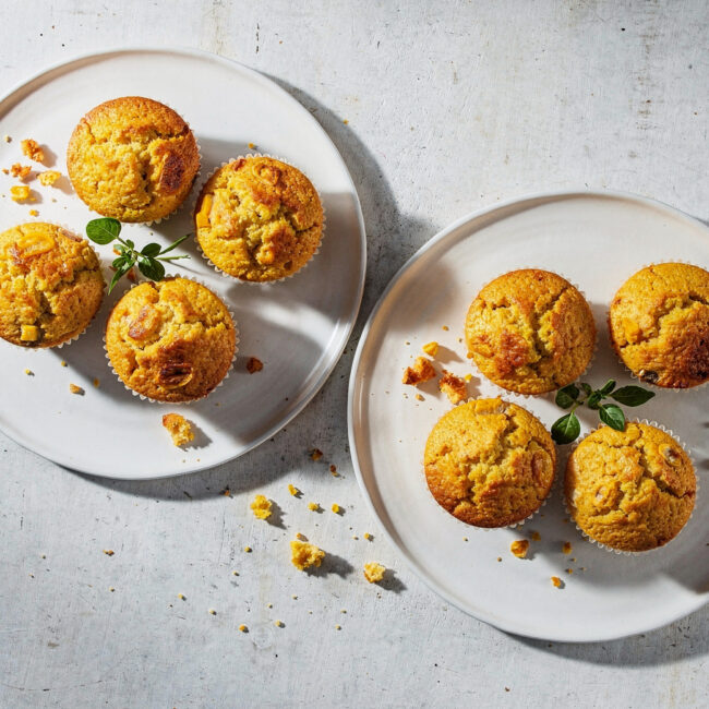 Freshly baked homemade corn muffins with a golden-brown crust on a rustic wooden table.