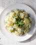 A creamy bowl of homemade potato salad with fresh herbs on a rustic wood table.