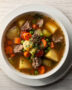 A steaming bowl of hearty homemade vegetable beef soup filled with tender beef and colorful vegetables.