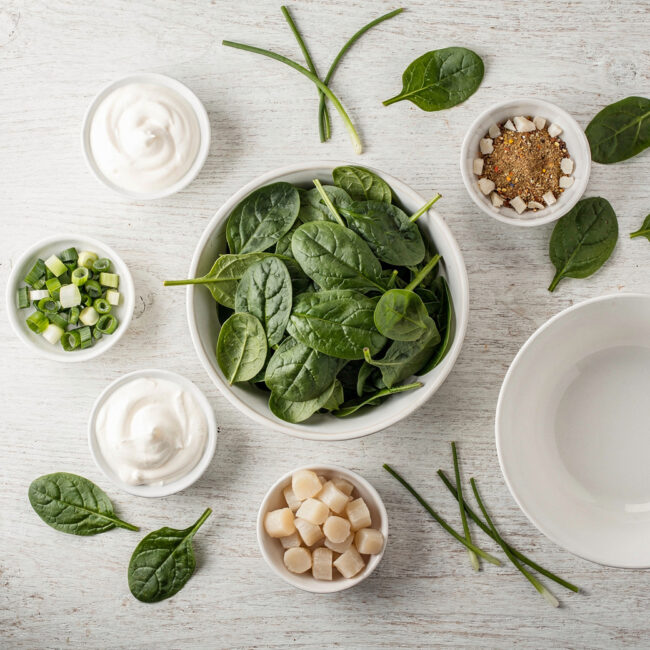 A vibrant overhead shot showing all the ingredients for knorr spinach dip arranged neatly on a wooden table.
