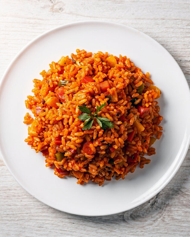 A vibrant bowl of knorr spanish rice soup, topped with cheese and cilantro, sits on a rustic wooden table.