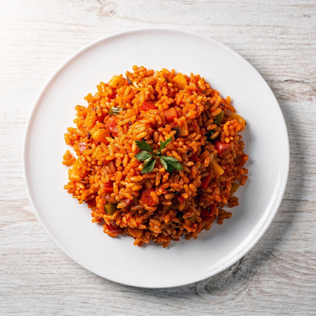 A vibrant bowl of knorr spanish rice soup, topped with cheese and cilantro, sits on a rustic wooden table.