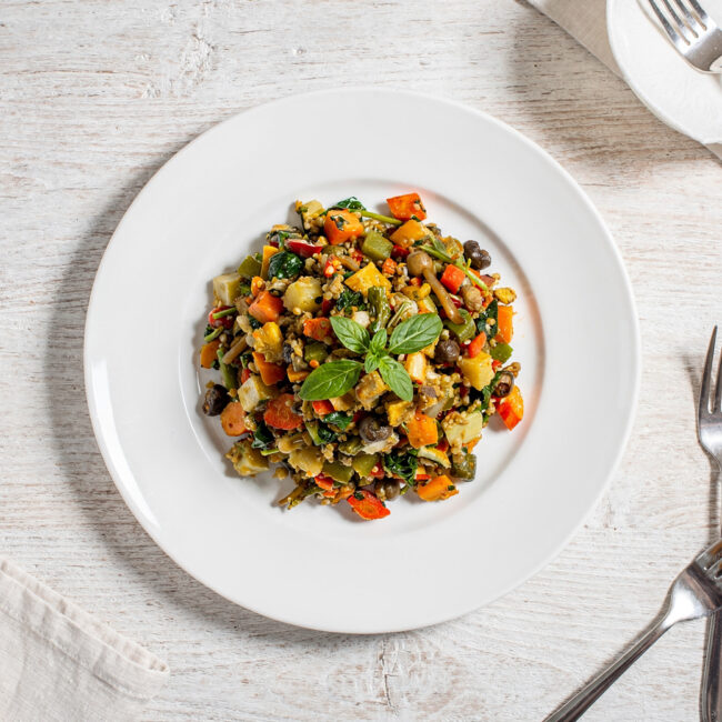 A creamy bowl of potato and leek soup made with knorr vegetable recipe mix, garnished with chives, on a rustic wooden table.