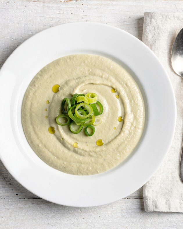 A creamy bowl of leek soup garnished with crispy pancetta and fresh thyme, ready to be enjoyed.