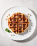 Freshly made liege waffle recipe dusted with powdered sugar on a rustic wooden board.