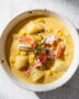 A steaming bowl of rich lobster corn chowder garnished with fresh chives.