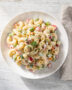 A vibrant, creamy macaroni salad with colorful vegetables, beautifully styled on a rustic wooden table.