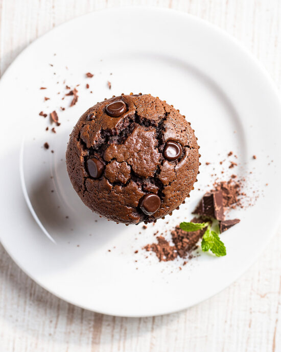 Freshly baked batch of this ultimate moist chocolate muffin recipe on a wooden board.