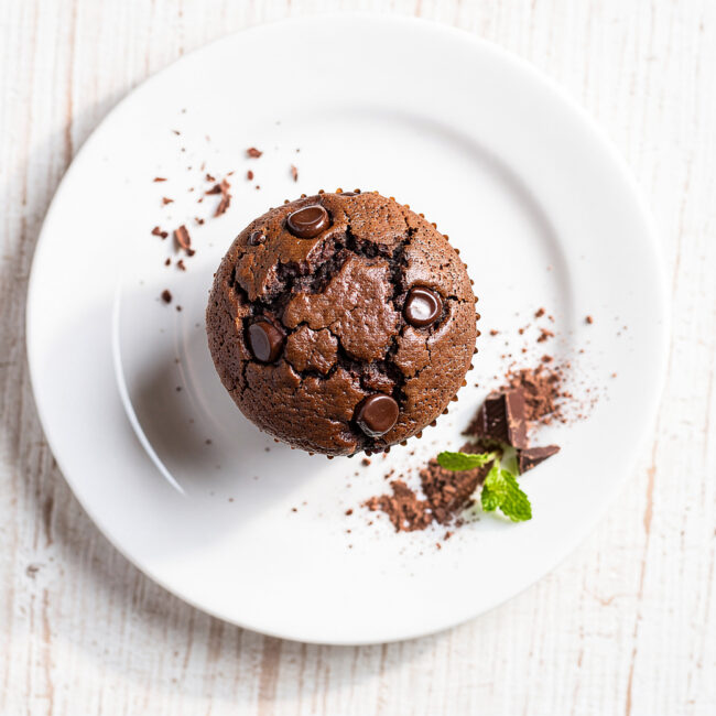 Freshly baked batch of this ultimate moist chocolate muffin recipe on a wooden board.