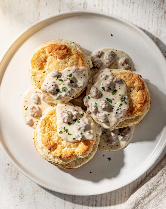 A golden, flaky biscuit split open and generously smothered with creamy sausage gravy in this pioneer woman biscuits and gravy recipe.