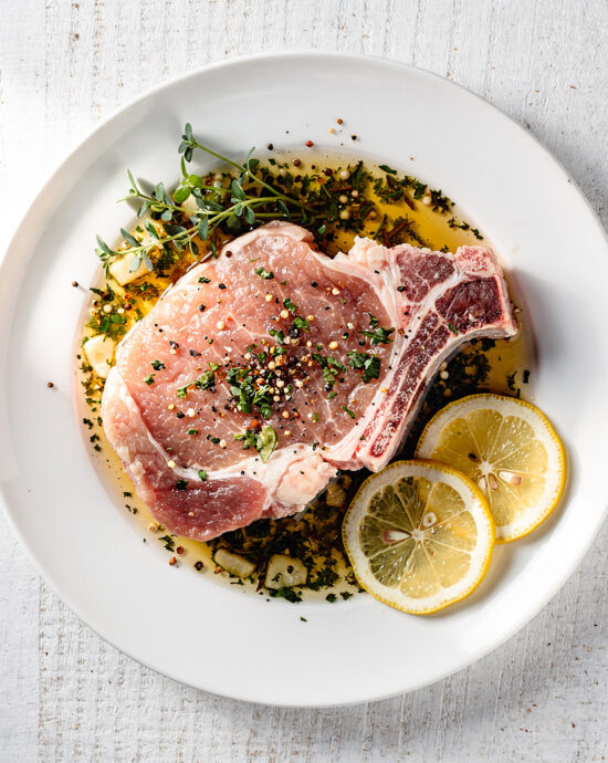 A close-up shot of golden-brown pork chops glistening with a honey and sage pork chop marinade.
