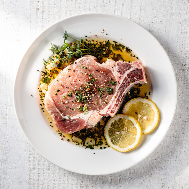 A close-up shot of golden-brown pork chops glistening with a honey and sage pork chop marinade.