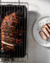 Slices of perfectly cooked pork loin on charcoal grill rest on a wooden cutting board, ready to serve.
