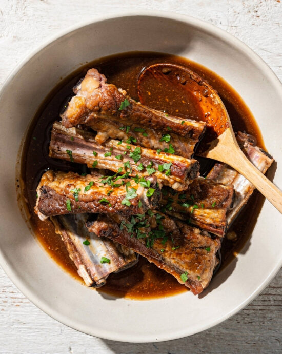 A bowl of rich, dark pork ribs marinade sits ready to transform a rack of ribs on a rustic wooden table.