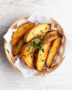 A heaping basket of golden brown potato wedges sprinkled with parsley, ready for dipping.
