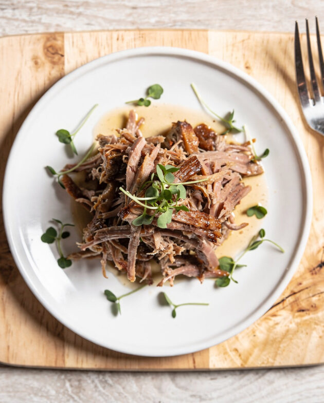 A beautifully plated pulled pork recipe on a rustic wooden board, ready to be served.