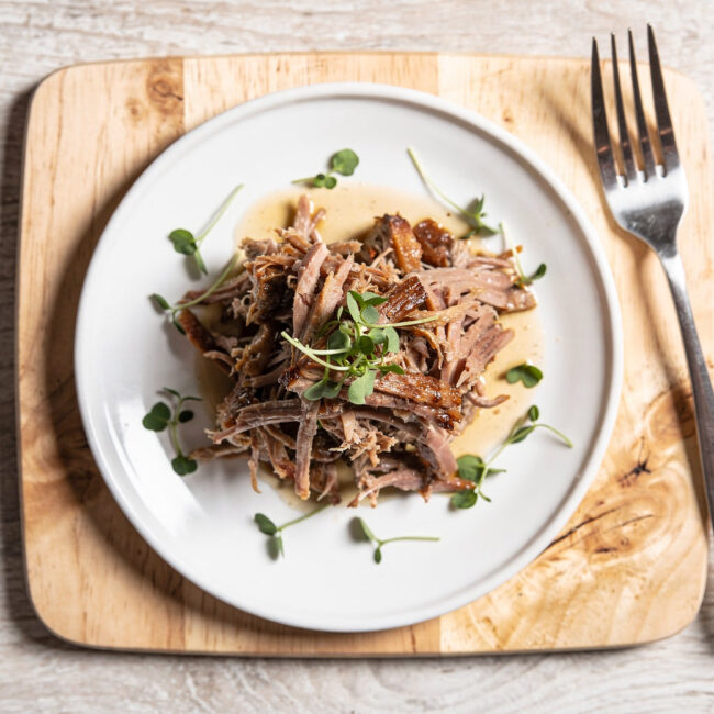 A beautifully plated pulled pork recipe on a rustic wooden board, ready to be served.