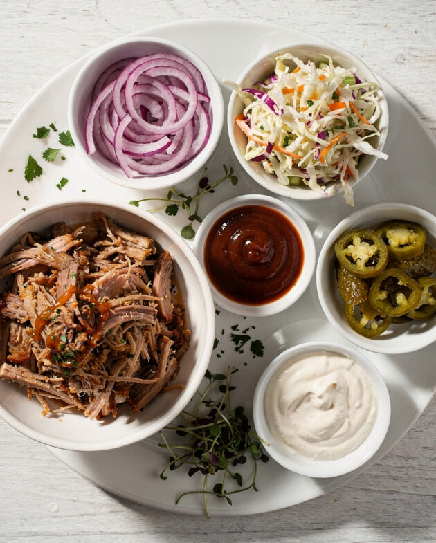 A top-down view of vibrant, creamy coleslaw pulled pork sandwich toppings in a white bowl, ready to crown a sandwich.