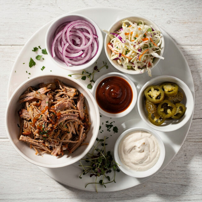 A top-down view of vibrant, creamy coleslaw pulled pork sandwich toppings in a white bowl, ready to crown a sandwich.