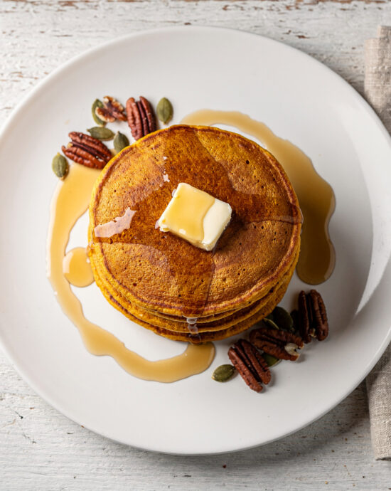 A golden stack of fluffy pumpkin pancakes drizzled with maple syrup, showcasing the perfect execution of this pumpkin pancake recipe.