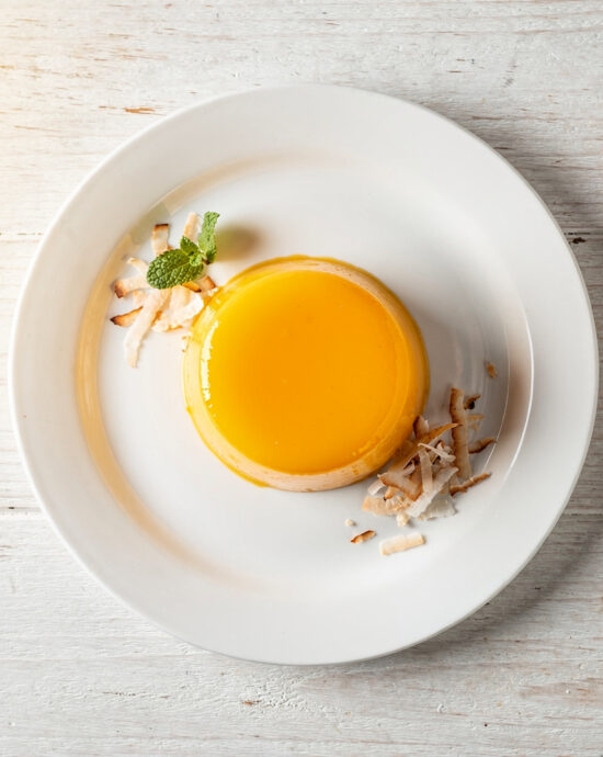 A perfectly baked quindim recipe, glistening with a golden top and served on a simple white plate.