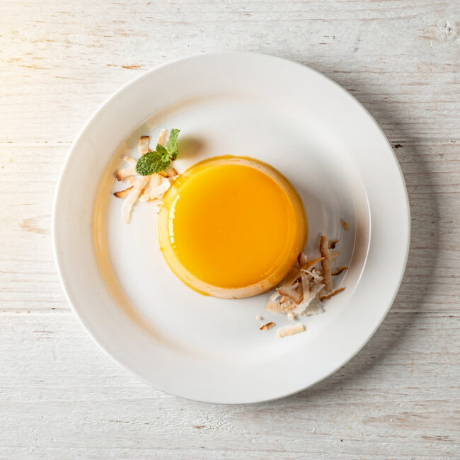 A perfectly baked quindim recipe, glistening with a golden top and served on a simple white plate.