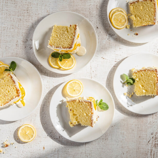 A slice of moist lemon drizzle cake made from easy recipes with lemon cake mix, resting on a wooden board.
