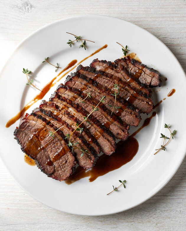 A perfectly cooked roasted brisket recipe, sliced and glistening with savory juices on a wooden board.